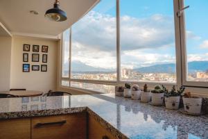 a kitchen with large windows and a counter with potted plants at Wanderlot - Departamento Leganza - Penthouse Lujoso in Riobamba