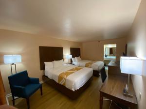 a hotel room with two beds and a blue chair at Quality Inn in Pulaski