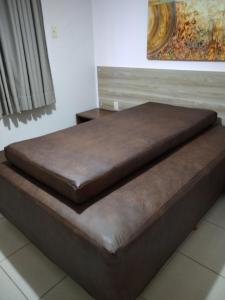 a bed with a brown leather seat in a room at Aldeia do Lago C104- Churrasqueira, bebidas liberadas nas piscinas, internet no ap, rampa no lago, pesqueiro, carregador carro elétrico in Caldas Novas +59 photos