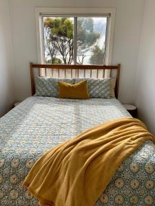 Una cama con una manta en una habitación con ventana en Salty Dog, en Emu Bay