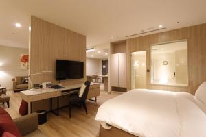 Schlafzimmer mit einem Bett, einem Schreibtisch und einem TV in der Unterkunft AJ Hotel Hsinchu in Zhubei