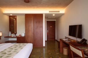 a hotel room with a bed and a desk with a television at Penh House Hotel in Phnom Penh