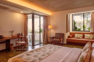 a bedroom with a bed and a desk and a window at Penh House Hotel in Phnom Penh