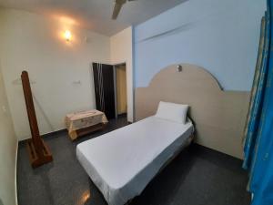 een slaapkamer met een wit bed in een kamer bij Daisey Dee Homestay in Madikeri