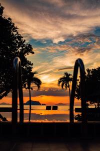 einen Sonnenuntergang über einem Wasserkörper mit Palmen in der Unterkunft Yao Yai Beach Resort in Ko Yao Yai