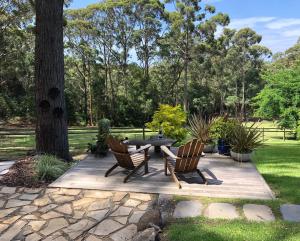 a patio with two chairs and a table in a park at The Ridge Retreat at Mollymook in Mollymook