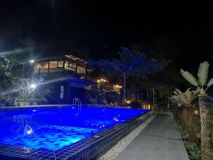 a house with a swimming pool at night at Keeree Loft Resort in Thong Pha Phum