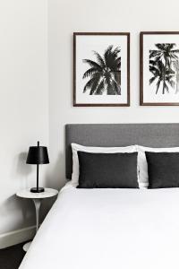 St Marks Randwick في سيدني: غرفة نوم بسرير ابيض مع وجود صورتين على الحائط