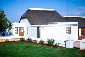 a white house with a thatched roof at Steynshoop self-catering Valley Lodge in Hekpoort