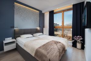 a bedroom with a large bed and a large window at Apartamenty Apartinfo Aura in Gdańsk