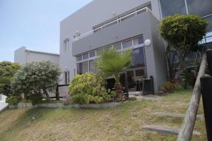 a house with a palm tree in front of it at Holiday apartment - 2min from beach (Melkbosstrand, Cape Town) in Melkbosstrand