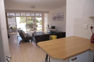 a kitchen and living room with a table and chairs at Holiday apartment - 2min from beach (Melkbosstrand, Cape Town) in Melkbosstrand