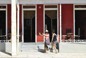 two people standing outside of a red building at Hotel Loro Tuerto in Santa Cruz de Barahona