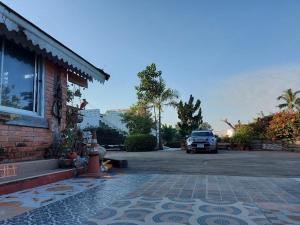 ein Auto, das auf einem Parkplatz neben einem Gebäude parkt in der Unterkunft Scenic Riverside Resort in Kamphaeng Phet