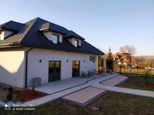 a white house with a black roof and a walkway at Zajazd ,,RYŚ'' in Dobra