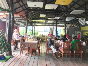 a group of people sitting at tables in a restaurant at Ricci House Resort in Ko Lipe