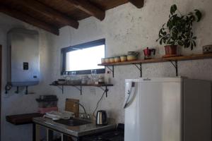 uma cozinha com um frigorífico, um lavatório e uma janela em La casa de la paz em Potrerillos