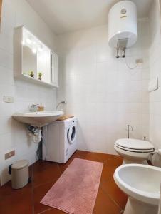 Baño blanco con lavabo y aseo en Appartamento il Sole, en Ponte di Legno
