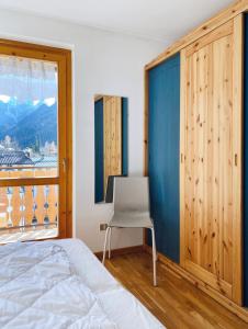 1 dormitorio con 1 cama, 1 silla y 1 ventana en Appartamento il Sole, en Ponte di Legno