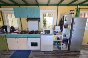 cocina con armarios azules y nevera blanca en Maison à Saint-leu, vue exceptionnelle sur la baie et l'Océan à 2 minutes des plages, en Saint-Leu