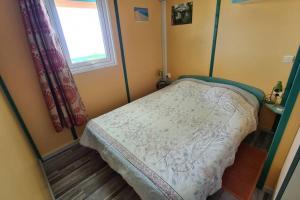 ein kleines Schlafzimmer mit einem Bett und einem Fenster in der Unterkunft Maison à Saint-leu, vue exceptionnelle sur la baie et l'Océan à 2 minutes des plages in Saint-Leu