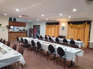 une salle de conférence avec des tables blanches, des chaises et des rideaux dans l'établissement Roundhouse Motel, à Peterborough