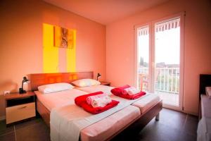 a bedroom with two beds with red sheets and a window at Apartments Kalaba - Dalma II in Podaca