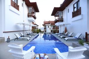 una piscina con sillas y sombrillas junto a un edificio en Alp Suites Pinehill, en Akyaka