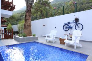 une maison avec une piscine, 2 chaises et un vélo dans l'établissement Alp Suites Pinehill, à Akyaka