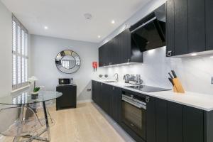 a kitchen with black cabinets and a glass table at Urban Chic - Wellington in London