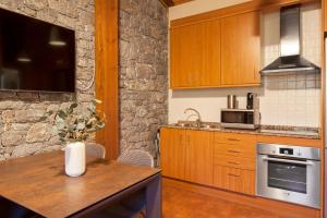 a kitchen with wooden cabinets and a wooden table at El Refugi de les Basses Apartament in Campelles