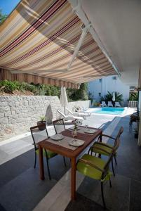 a patio with a wooden table and chairs under an umbrella at Apartments Kalaba - Dalma II in Podaca