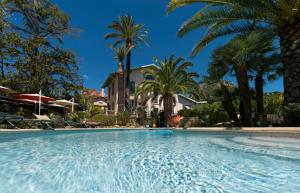 ein großer Swimmingpool mit Palmen im Hintergrund in der Unterkunft La Villa Roseraie , Hôtel Familial OUVERT TOUTE L'ANNEE in Vence