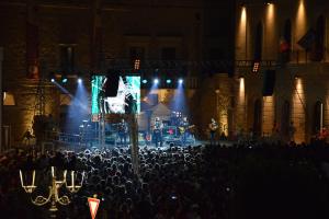 una multitud de personas viendo un concierto por la noche en Palazzo Rimesa en Cutrofiano