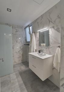 ein weißes Badezimmer mit Waschbecken und Spiegel in der Unterkunft Malibú Canteras nº 1 - Planta Baja - Ground Floor in Las Palmas de Gran Canaria
