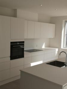 a white kitchen with white cabinets and a sink at Hus med søudsigt in Brabrand +8 photos