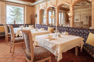 un restaurant avec deux tables, des chaises et des fenêtres dans l'établissement Hotel Seelos, à Seefeld in Tirol