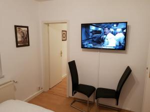 Zimmer mit einem TV an einer Wand mit 2 Stühlen in der Unterkunft SchlafSchön Apartments+Monteurzimmer in Böhlen