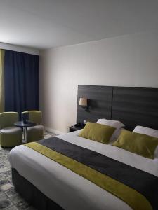 エヴルーにあるBest Western Plus Evreux Palais Des Congrèsの大きなベッドと椅子が備わるホテルルームです。