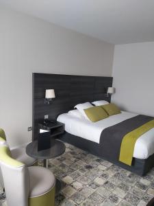 a bedroom with a large bed and a table and chairs at Best Western Plus Evreux Palais Des Congrès in Évreux