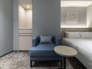 um quarto com uma cama e uma cadeira azul em HOTEL FORZA SAPPORO STATION em Sapporo