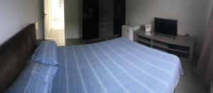 um quarto com uma cama azul e uma televisão em Vander's House em Niterói