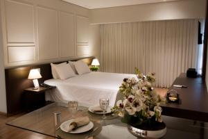 Santorini Hotel في Guanhães: غرفة نوم بسرير وطاولة مع صحون وكاسات