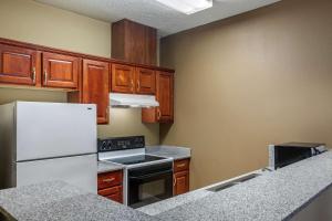a kitchen with a white refrigerator and wooden cabinets at Comfort Suites The Colony - Plano West in The Colony