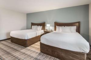 um quarto de hotel com duas camas com lençóis brancos em MainStay Suites em Union City