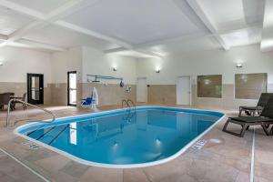 - une grande piscine dans une pièce avec une table et des chaises dans l'établissement Comfort Suites Auburn near I-69, à Auburn