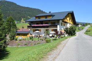 ein Haus auf einem Hügel neben einer Straße in der Unterkunft Gästehaus Tannegg in Mittelberg