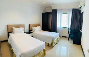a hotel room with two beds and a window at Likas Square - KK Spacious Homestay in Kota Kinabalu