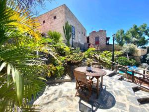 un patio con mesa y bancos y un edificio en Casa Rural La Cuadra, en Las Vegas