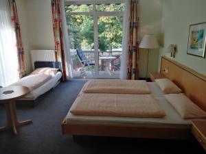 a bedroom with two beds and a table and a window at Kurparkhotel Das Kleinod in Bad Kissingen